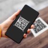 Ruka která drží v ruce mobilní telefon a skenuje QR kód